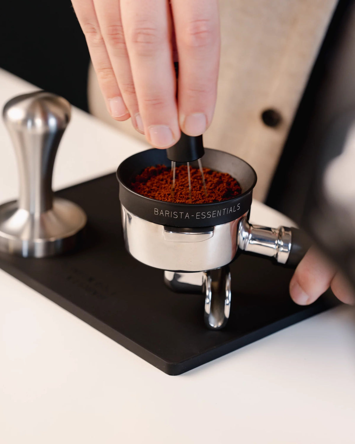 Vlakke tampermat van Barista Essentials waar puck prep wordt gedaan met een portafilter, tamper, WDT-tool en doseerring